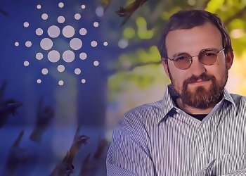 Picture of Cardano founder Charles Hoskinson next to a Cardano logo with hands pointing up to it