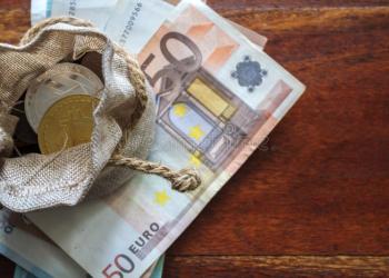 Picture of a small purse with crypto coins in it sitting on top of a stack of €50 notes, depicting MrBeast crypto holdings