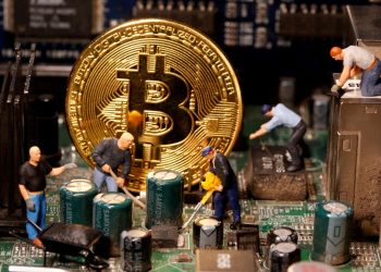 Picture of a gold bitcoin on a circuit board with figurine miners around it