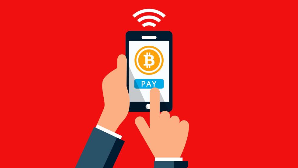 Picture of a hand holding a cellphone paying with bitcoin