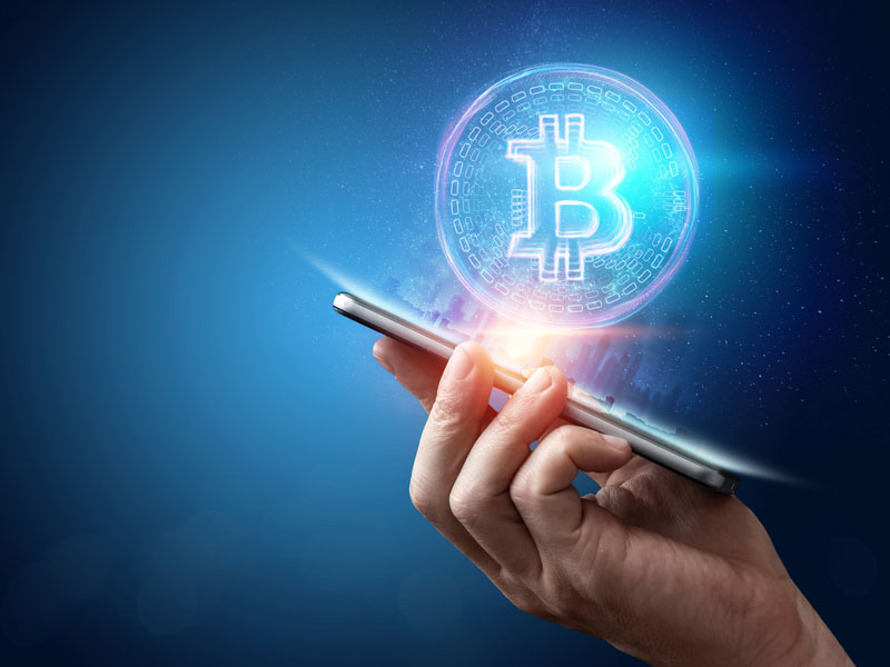 handing holding cellphone with cryptocurrency over it