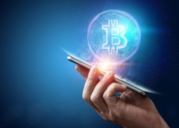 handing holding cellphone with cryptocurrency over it